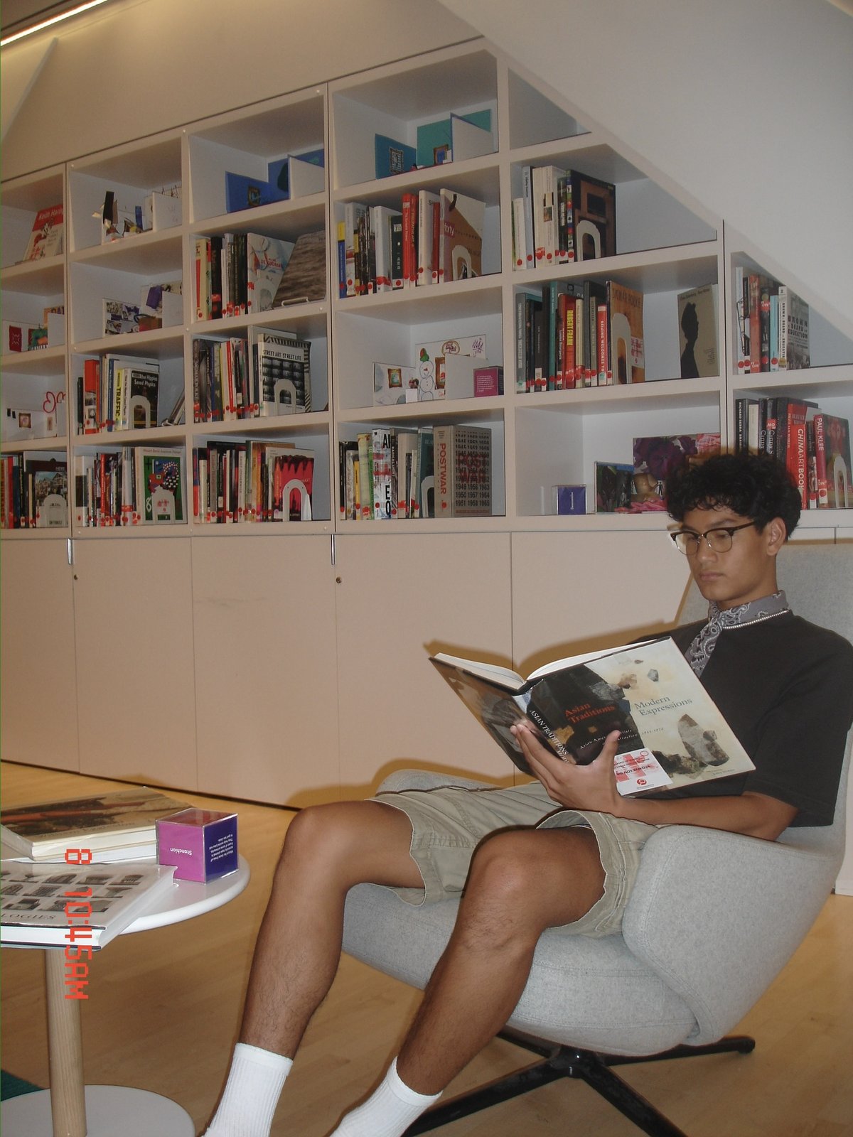 Darrell Cenido reading in a library surrounded by books